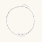 Sterling silver multi-strand necklace with three brushed round beads on cream background